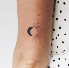 a woman's arm with a small sun and moon tattoo on it