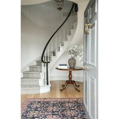 a table with a vase on it in front of a stair case next to a door