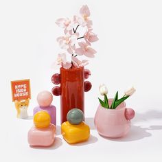 there is a vase with flowers in it next to two small figurines and a sign