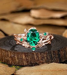 a green ring sitting on top of a piece of wood next to leaves and stones