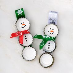 two snowmen made out of golf balls on a white surface with green and red ribbon