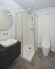 a bathroom with a toilet, sink and shower stall in it's own area