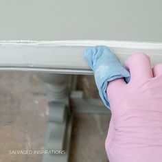 a person in pink gloves wiping off the edge of a white door with a blue cloth