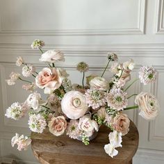 a vase filled with lots of pink and white flowers on top of a wooden table