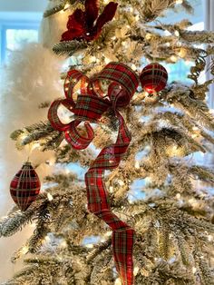 a christmas tree decorated with red and white plaid ribbon, ornaments and bows on it