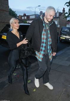 the man and woman are walking down the street together, one is wearing black tights