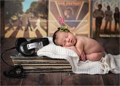 a baby sleeping on top of a pile of books next to headphones and an old record player