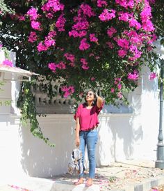 a woman standing in front of a tree with pink flowers