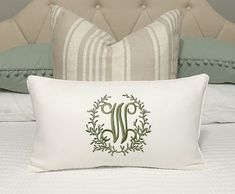 a white pillow with a monogrammed letter on it sitting on top of a bed