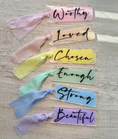 five different colored hair ties on top of a wooden table with writing written on them