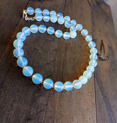 "Opaline Moonstone Necklace. White Opalite Gemstone Jewelry. Beaded necklace. One strand. Opal jewelry. Handmade, white Opaline moonstone gemstone beaded necklace. Beautiful, round polished beads are 10 mm in diameter. Beads are flashing with yellow and blue lights depending g on the source of light. Sterling silver plated clasp. Length is 18\" on a mannequin, plus 2\" extender. This gorgeous necklace comes in a complimentary, beautiful jewelry box ready for gift giving. All mailing supplies are Beaded Moonstone Round Necklace, White Moonstone Beaded Necklaces With Round Beads, Elegant White Moonstone Beaded Necklaces, Elegant White Moonstone Beaded Necklace, White Opal Necklace With Natural Stones, White Opal Bead Necklaces, White Opal Round Bead Necklaces, White Opal Round Beads Necklace, White Beaded Opal Jewelry