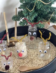 some glass jars filled with sand and fake reindeer noses are sitting in front of a christmas tree