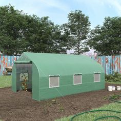 a large green building sitting in the middle of a field next to a blue fence