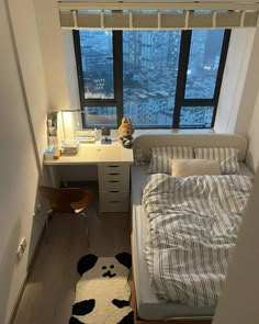 a bed room with a neatly made bed and a desk in front of a window