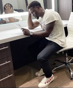 a man sitting at a desk in front of a mirror looking at his cell phone