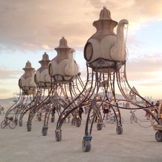 an art installation made out of bicycles and people riding bikes on the beach at sunset