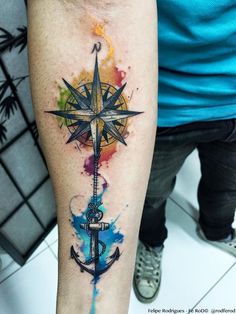 a watercolor tattoo with an anchor and compass on the arm, painted in bright colors