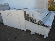 a pile of metal pipes sitting on top of a tarp next to a building