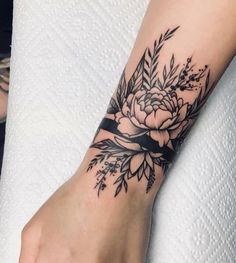 a woman's hand with a flower tattoo on her left wrist and the other arm