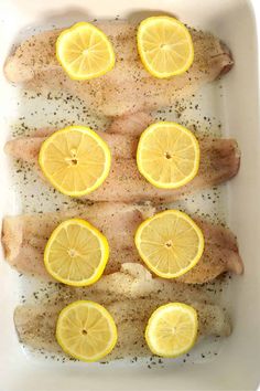 fish with lemons and seasoning in a white dish