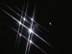 the sun shines brightly in the dark sky above some thin strips of light that appear to be intersecting