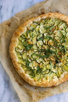 a pizza with zucchini and other toppings on top of parchmented paper