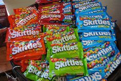 a basket full of skittles sitting on top of a table next to other snacks