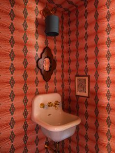 an old fashioned sink in the corner of a room with wallpaper and pictures on the walls