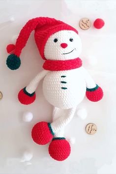 a knitted snowman ornament with red and white pom - poms