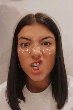 a girl with stars painted on her face making a funny face while looking at the camera