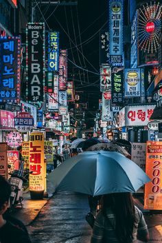 a woman holding an umbrella in the middle of a city at night with neon signs all around her