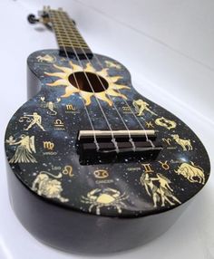 a black ukulele with zodiac symbols on it