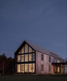 a house that is lit up at night with windows on the front and side of it