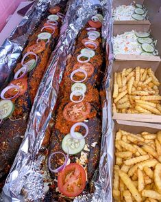 two trays filled with different types of food on tin foil lined up next to each other