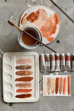 an artist's palette with paints and brushes next to it on a cement surface