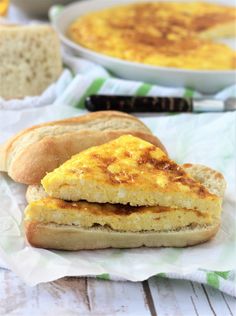 an omelet sandwich is on a piece of paper next to a bowl of soup