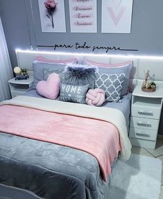 there is a bed with pink and gray pillows on it, along with two pictures above the bed