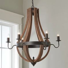 a wooden chandelier hanging from a ceiling in a room with white walls and windows