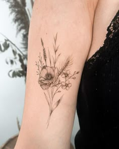 a woman's arm with flowers and leaves tattoo on the left side of her arm