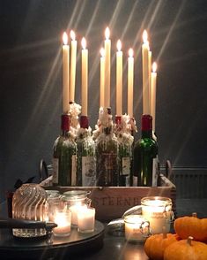 candles are lit in front of bottles and pumpkins on a table with other items