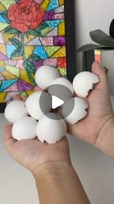 a person holding several white eggs in front of a stained glass painting on the wall