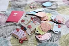 many pieces of paper are laying on a quilted tablecloth with hearts and tags attached to them