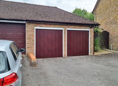 two garage doors are open in front of a brick building with a car parked next to it