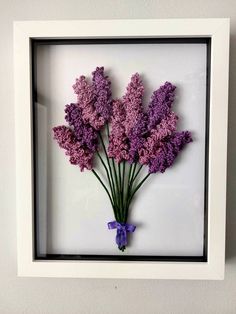 purple flowers are arranged in a shadow box