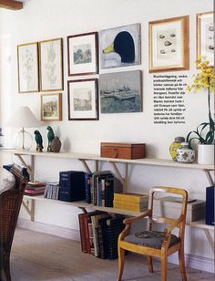 a room with pictures on the wall and some chairs in front of bookshelves