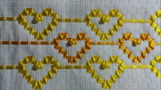 some yellow and orange beads are on a white table cloth with an intricate design in the middle