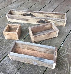 three wooden boxes sitting on top of a wooden floor next to each other with dirt in them