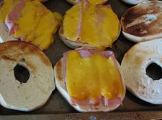 several bagels with ham and cheese on them are sitting in a baking pan, ready to be cooked