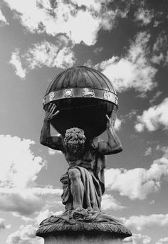 black and white photograph of a statue holding a bowl on top of it's head