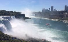 a boat is in the water next to a large waterfall with people standing on it